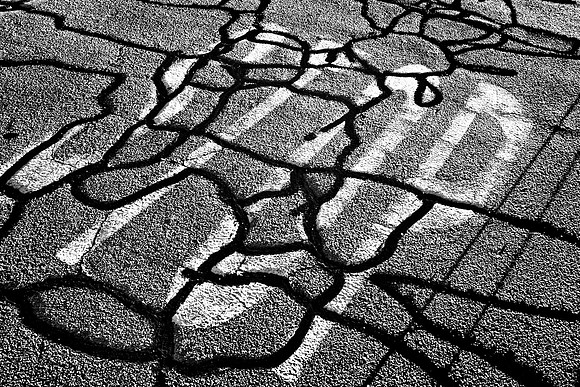 The word STOP is painted on an asphalt road with squiggly crack repairs meandering across it.